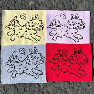 May include: Four square fabric patches arranged in a grid, each featuring a black ink illustration of a cartoon dog with multiple legs and a small speech bubble. The background colors of the patches are pale yellow, light purple, gray, and red.