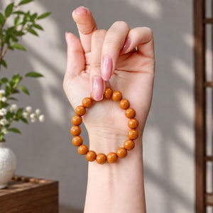 May include: A stretch bracelet composed of smooth, round, mustard-yellow beads. The beads are uniform in size and shape, strung together to form a circular band that fits around the wrist. The surface of each bead has a consistent matte finish.