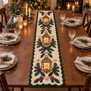 May include: A cream-colored crocheted table runner featuring a repeating pattern of brown lanterns with yellow flames, surrounded by green pine branches and red berries, finished with a scalloped dark green border along the entire edge.