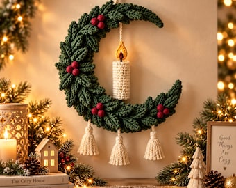 May include: A crescent moon-shaped wall hanging crafted from dark green crocheted leaves and red berries. A white crocheted pillar candle with a yellow and orange flame sits in the center. Three white crocheted tassels hang from the bottom edge.