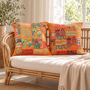 May include: Two square throw pillows featuring a vibrant patchwork design with various orange, pink, green, and blue fabric segments. The pillows are decorated with intricate embroidery, metallic thread accents, and diverse floral and geometric patterns.