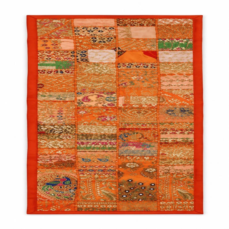 May include: A rectangular wall hanging featuring a patchwork of orange fabric squares with varied embroidery, sequins, and metallic thread patterns. The piece is framed by a solid orange border and includes intricate floral and peacock motifs.