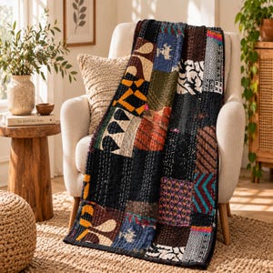 May include: A rectangular patchwork quilt featuring a variety of fabric squares with diverse patterns and colors, including black, blue, orange, and white, stitched together with visible white running thread throughout the entire surface.