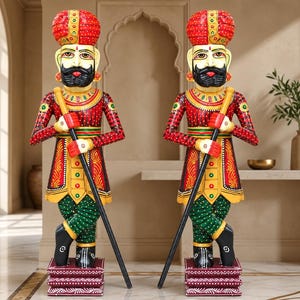 Puede incluir: Dos estatuas de madera idénticas pintadas a mano de guardias con turbantes rojos, túnicas rojas con detalles en amarillo y verde, y pantalones verdes. Cada figura se apoya en una base cuadrada, sostiene un bastón negro y tiene bigote negro.