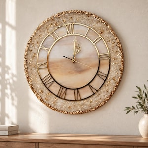 May include: A round wall clock featuring a central face with a beige and white marbled pattern, surrounded by a textured border of crushed clear crystals and gold leaf flakes. It has thin gold Roman numerals and gold hands.