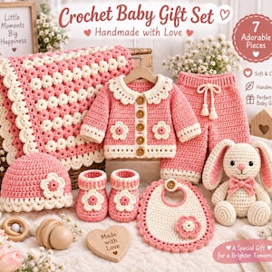 May include: A crochet baby gift set featuring a pink and cream blanket, a long-sleeve cardigan with wooden buttons, matching pants, a beanie, booties, a bib, and a stuffed rabbit. Each item is decorated with floral accents and scalloped edges.