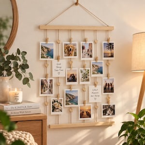 Peut inclure: Un présentoir mural pour photos composé de deux barres horizontales en bois clair reliées par des cordes de jute verticales. De petites pinces en bois et des perles en forme de cœur maintiennent des photos carrées et deux cartes blanches.