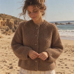 Könnte beinhalten: Eine braune Strickjacke mit Rundhalsausschnitt, langen Ärmeln mit gerippten Bündchen und einer Knopfleiste auf der Vorderseite mit fünf passenden braunen Knöpfen. Das Kleidungsstück hat eine strukturierte Strickoptik und einen geraden Saum.