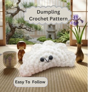 Può includere: Un raviolo all'uncinetto bianco con occhi a perla neri e una bocca ricamata. L'immagine contiene il testo Dumpling Crochet Pattern e Easy To Follow. Il raviolo è posizionato su un tappetino intrecciato accanto a una bambola di legno e una tazza.
