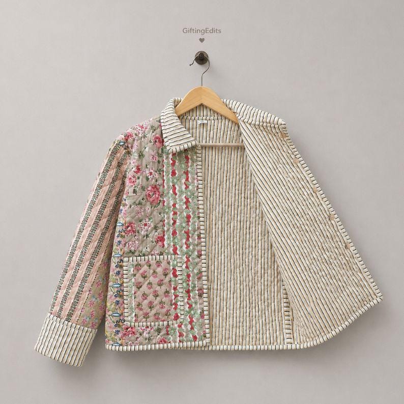 May include: A quilted jacket featuring a patchwork design with floral patterns in pink, green, and beige, contrasted by black and white vertical stripes on the sleeves, collar, and interior lining. The jacket includes a front pocket and button closure.