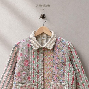 May include: A quilted jacket featuring a patchwork design of floral and striped patterns in shades of pink, green, and tan. The garment has a collared neckline with a striped trim, a button-down front, and two front pockets. The text GiftingEdits is visible.