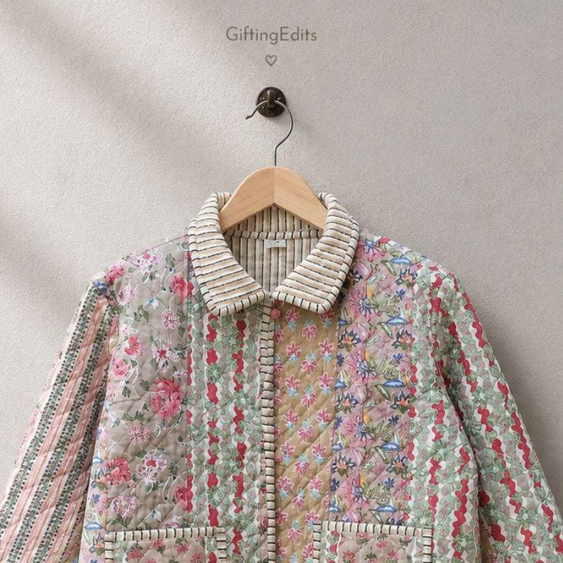 May include: A quilted jacket featuring a patchwork design of floral and striped patterns in shades of pink, green, and tan. The garment has a collared neckline with a striped trim, a button-down front, and two front pockets. The text GiftingEdits is visible.