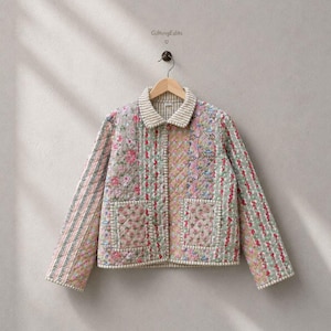 May include: A quilted jacket featuring a patchwork design of floral patterns in shades of pink, green, and blue. The jacket has a collared neckline, long sleeves, two front patch pockets, and a button-down front closure. The text GiftingEdits is visible.