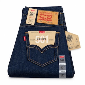 May include: Dark blue denim jeans with a straight leg fit. Features include a tan leather-like patch with Levi Strauss & Co. branding, a 501 Original paper tag on the back pocket, a red tab, and multiple product labels indicating a 30x30 size.