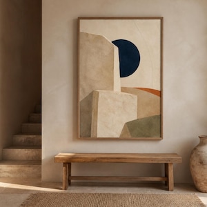 May include: A framed rectangular wall art print featuring an abstract landscape with geometric beige stone structures, a solid dark blue circle, and horizontal bands of muted orange and olive green set against a light cream background.