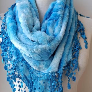 May include: A blue and white ombre scarf with a blue crocheted trim. The scarf is soft and fluffy and would be perfect for keeping warm in the winter.