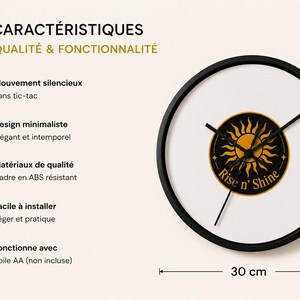 Puede incluir: Un reloj de pared redondo con marco negro y esfera blanca que presenta un emblema circular negro central con un gr&aacute;fico de sol amarillo y el texto Rise n' Shine. El reloj tiene manecillas negras, un di&aacute;metro de 30 cm y texto con funciones.