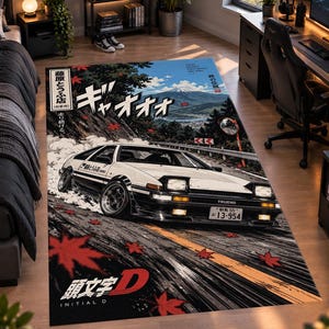 May include: A rectangular area rug featuring a white and black sports car drifting on a mountain road with red maple leaves, Mount Fuji in the background, Japanese text, and the Initial D logo printed in the bottom corner on a dark background.