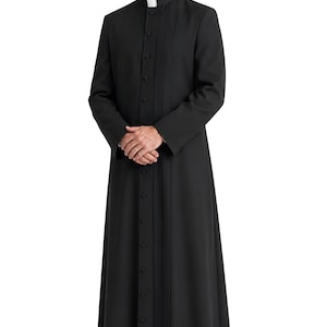 May include: A black cassock featuring a high mandarin collar with a white clerical tab insert, long sleeves, and a full-length front button closure. The garment includes vertical pleats running down the front, creating a structured appearance.