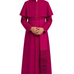May include: A magenta cassock featuring a standing collar, a row of matching buttons down the front, and a short capelet over the shoulders. A wide matching sash with long, decorative fringe hangs from the waist, paired with black dress shoes.
