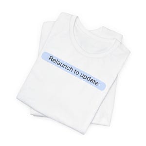 May include: A white short-sleeved t-shirt featuring a light blue horizontal rectangular graphic on the chest. The graphic contains the black text "Relaunch to update" centered within the blue shape. The shirt is folded neatly to display the front.