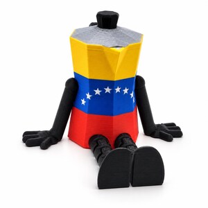 May include: A 3D-printed figurine shaped like a moka pot coffee maker, featuring the yellow, blue, and red colors of the Venezuelan flag with a central arc of white stars. The figure has black articulated arms, hands, and legs with flat feet.
