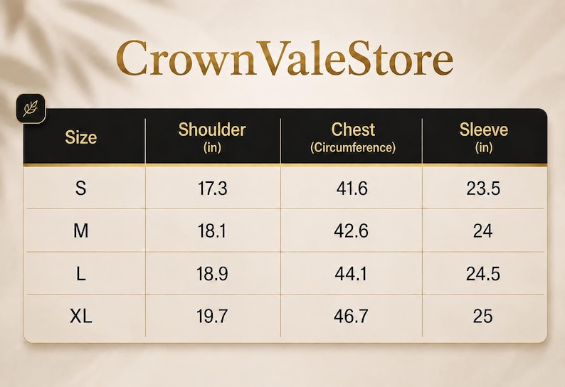 Op de afbeelding: Een maattabel voor CrownValeStore met een zwart en cr&egrave;mekleurig overzicht. De kolommen tonen maat, schouder in inches, borstomtrek in inches en mouwlengte in inches. De rijen bevatten de afmetingen voor de maten S, M, L en XL in een tabel.