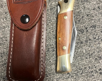 Navaja Camillus Lockback vintage de los años 70: cachas de madera, refuerzo de latón y funda de cuero.