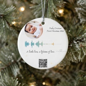 Może przedstawiać: Okrągła biała ceramiczna ozdoba z okrągłym zdjęciem dziecka, napisem Tudor Cristian First Christmas 2026, turkusowo-złotą grafiką fali dźwiękowej, frazą A little love, a lifetime of love, ikoną serca oraz kodem QR.