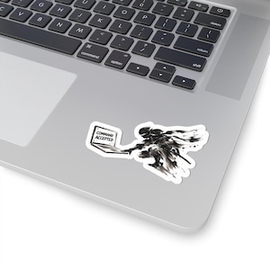 May include: A die-cut sticker featuring a black and white ink-style illustration of a ninja figure in a dynamic pose reaching toward an open laptop. The laptop screen displays the text COMMAND ACCEPTED in a bold, sans-serif font.