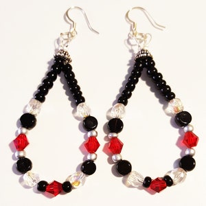 May include: A pair of teardrop-shaped earrings with black, red, and clear beads. The earrings have silver hooks and are made with a variety of bead sizes and shapes.
