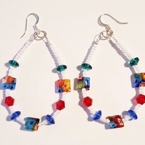 May include: A pair of dangle earrings with white seed beads, green, red, and blue glass beads, and colorful square glass beads.