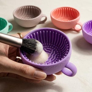 Op de afbeelding: Een set siliconen kommen voor het reinigen van make-upkwasten in diverse kleuren zoals paars, roze, turquoise en beige. Elke kom heeft een textuur aan de binnenzijde met ribbels en bobbels voor het reinigen van de haren.