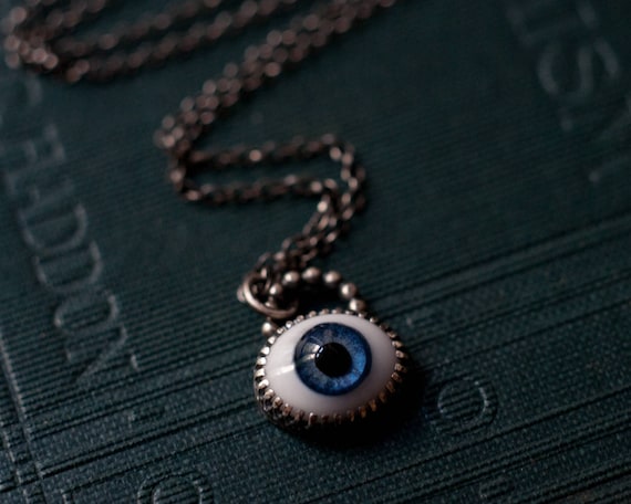 Evil eye necklace with a glass doll eye set into sterling silver, a magical protection amulet available in blue, green, grey or brown