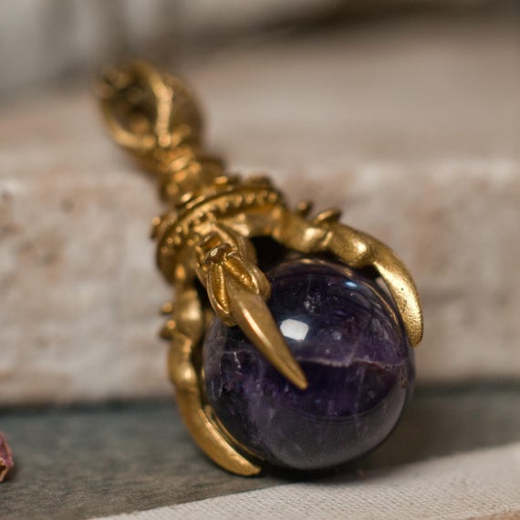 Brass claw and crystal ball fidget necklace with an amethyst sphere in antiqued brass.