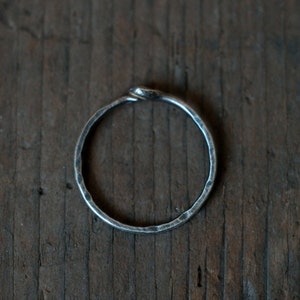 Op de afbeelding: Een zilveren ring met een gedraaide band, de ring is glad en heeft een gehamerde afwerking.