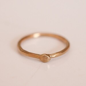 Op de afbeelding: Een eenvoudige gouden ring met een klein, rond, getextureerd accent.