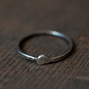 Op de afbeelding: Een eenvoudige zilveren ring met een gehammerde afwerking en een hartvormig detail.