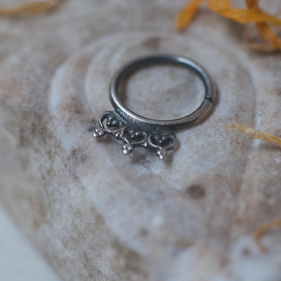 Sterling silver septum ring in 16 gauge oxidised 925 silver with a love heart and granulation pattern. The ring twists to open/close.