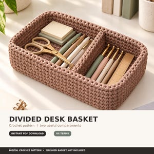 Puede incluir: Una cesta rectangular de ganchillo en color malva con dos compartimentos internos. La cesta contiene un taco de notas adhesivas cuadradas, unas tijeras doradas, varios bolígrafos, tres ganchillos y una pequeña regla de madera.