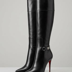 May include: A pair of black leather knee-high boots with a pointed toe and a high stiletto heel. The boots feature a decorative strap around the ankle with a silver-toned metal buckle detail and a signature bright red sole on the bottom.
