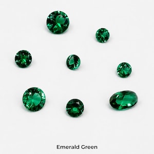 Eight faceted emerald green stones on a pale grey background: three 2.5 mm rounds,
two 3 mm rounds, two 4 mm rounds and one 4 x 6 mm oval, shown loose so the
dark green colour is visible. Labelled emerald green.