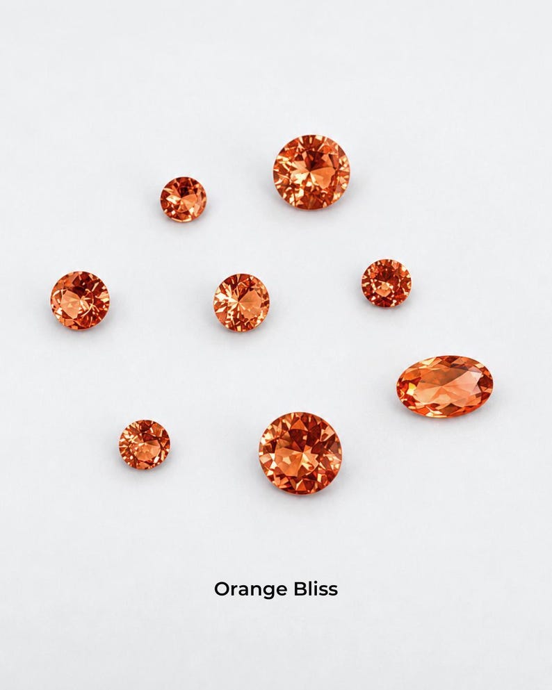 Eight faceted orange stones on a pale grey background: three 2.5 mm rounds,
two 3 mm rounds, two 4 mm rounds and one 4 x 6 mm oval, shown loose so the orange color is visible. Labelled orange bliss.