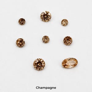 Eight faceted orange stones on a pale grey background: three 2.5 mm rounds,
two 3 mm rounds, two 4 mm rounds and one 4 x 6 mm oval, shown loose so the
champagne colour is visible. Labelled champagne.