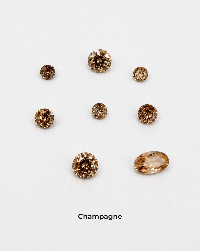 Eight faceted orange stones on a pale grey background: three 2.5 mm rounds,
two 3 mm rounds, two 4 mm rounds and one 4 x 6 mm oval, shown loose so the
champagne colour is visible. Labelled champagne.