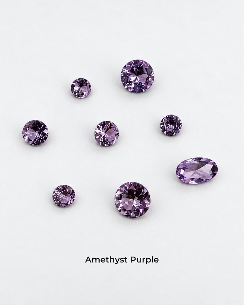Eight faceted purple stones on a pale grey background: three 2.5 mm rounds,
two 3 mm rounds, two 4 mm rounds and one 4 x 6 mm oval, shown loose so the
purple color is visible. Labelled amethyst purple.