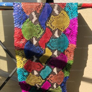 May include: A rectangular piece of snakeskin leather featuring a vibrant, multi-colored pattern. The scales are dyed in bright shades of red, blue, green, yellow, turquoise, and magenta, creating a bold, high-contrast mosaic effect across the surface.