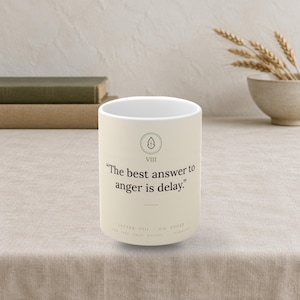 Könnte beinhalten: Ein cremefarbener Keramikbecher mit einem kreisförmigen Symbol mit einer Flamme über der römischen Ziffer VIII und dem aufgedruckten Zitat, "The best answer to anger is delay." Unter dem Zitat steht der Text, "LETTER VIII - ON ANGER THE FIRE THAT KNOWS HARMONY."