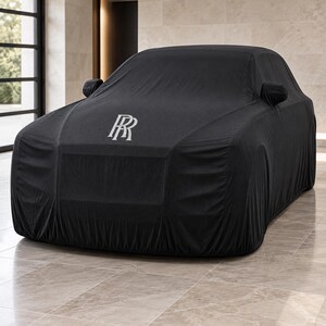 May include: A black car cover draped over a vehicle, featuring the silver Rolls-Royce RR monogram logo printed on the bonnet. The fabric is form-fitting, covering the entire exterior including the side mirrors, with a smooth, opaque texture.