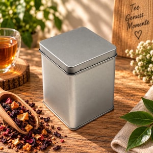 Puede incluir: Una lata de almacenamiento cuadrada de metal color plata con tapa a juego. El recipiente tiene un acabado mate liso y un diseño simple y limpio. Es un recipiente funcional para almacenar productos secos, con una construcción robusta.